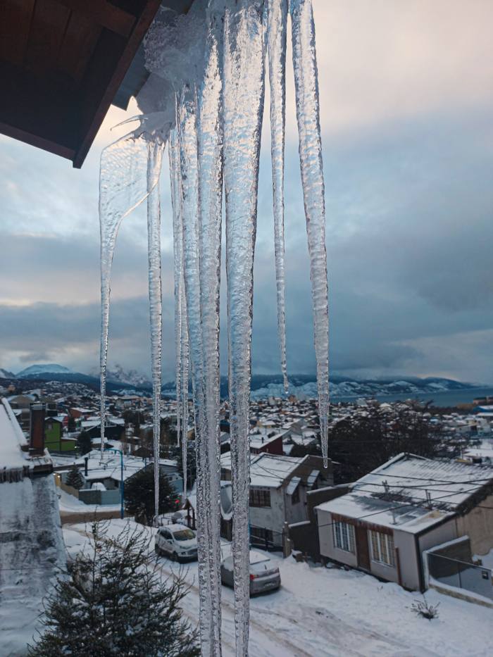 Carámbanos de hielo colgando de un alero, con la ciudad nevada abajo