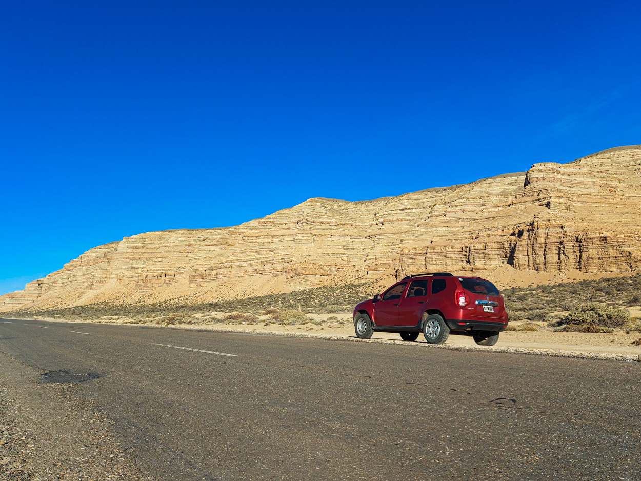 La camioneta roja detenida frente a las mesetas de estratos de Los Altares